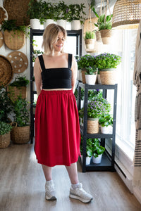 Haut noir et jupe midi rouge portés par la silhouette Claudie (M).